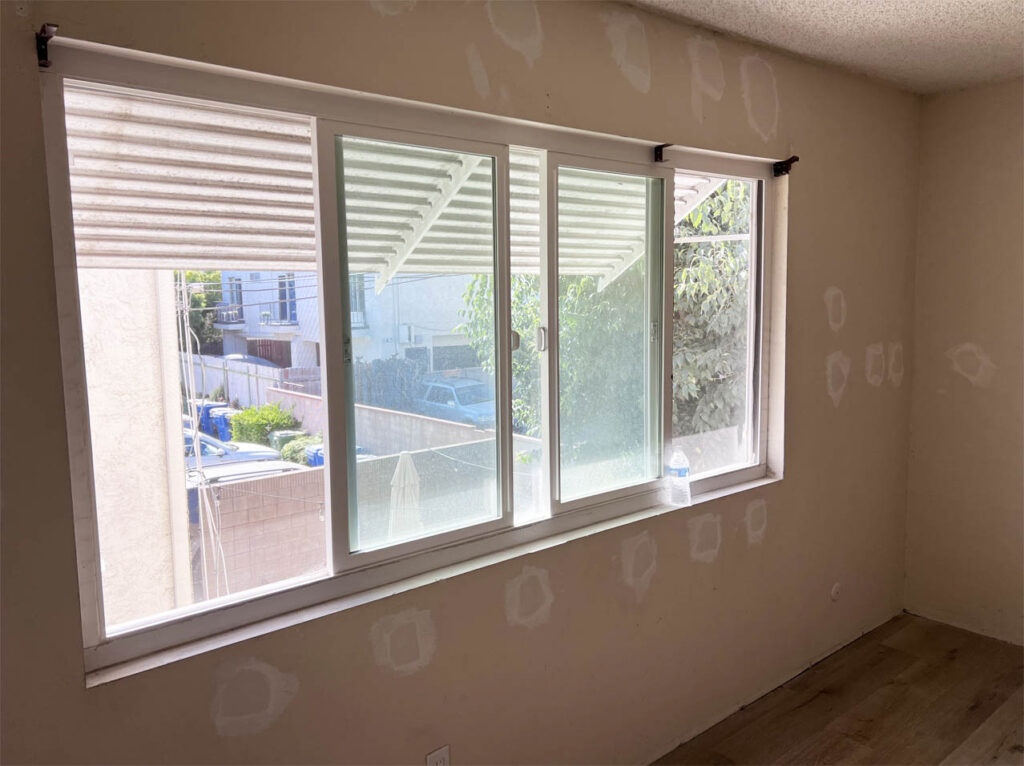 A newly renovated room with fresh insulation around large windows, reflecting a stage in construction focusing on enhancing thermal efficiency.
